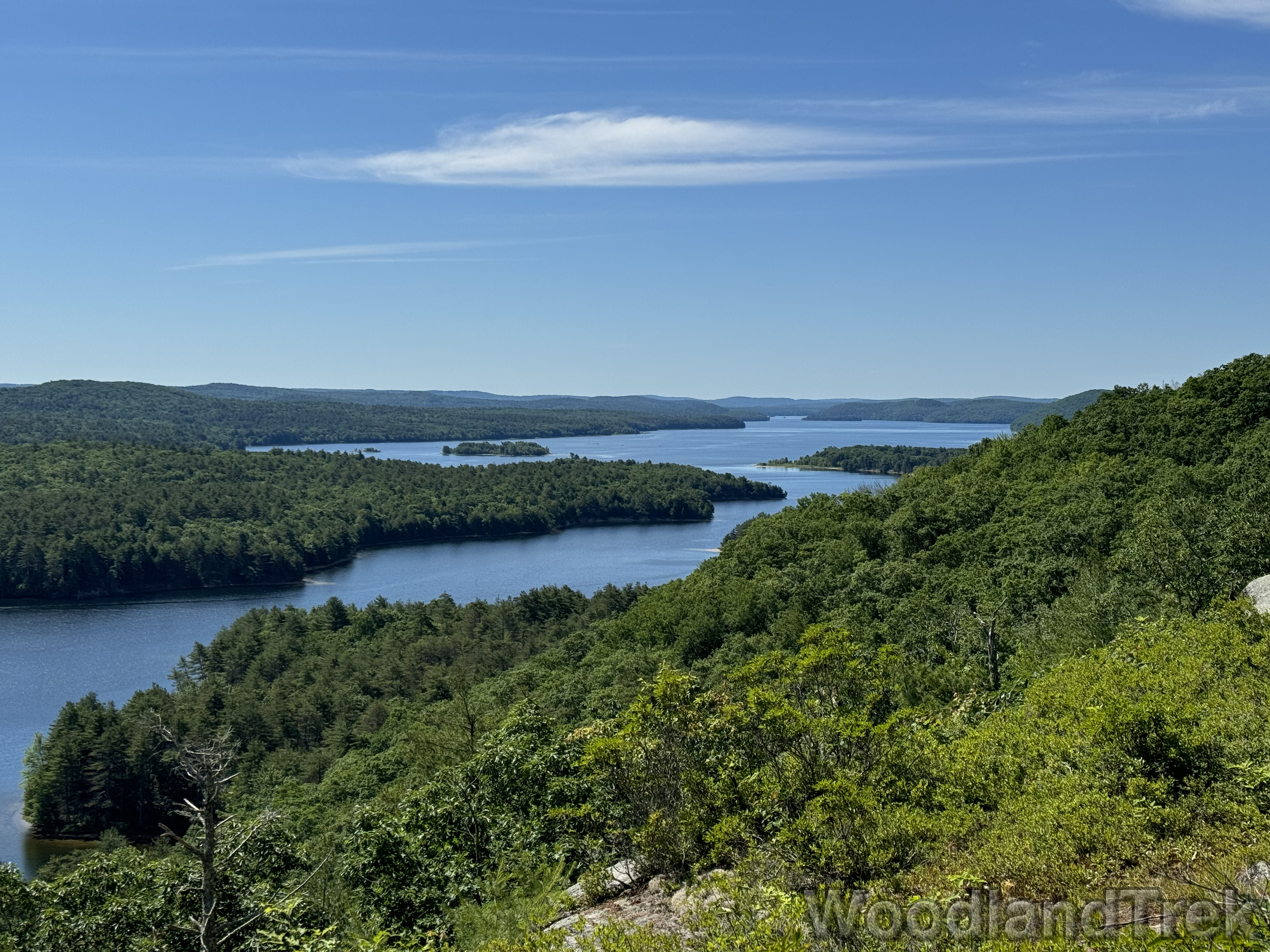 Expansive view of Quabbin Reservoir from Rattlesnake Hill, with deep blue water and rich green forests under bright sunlight