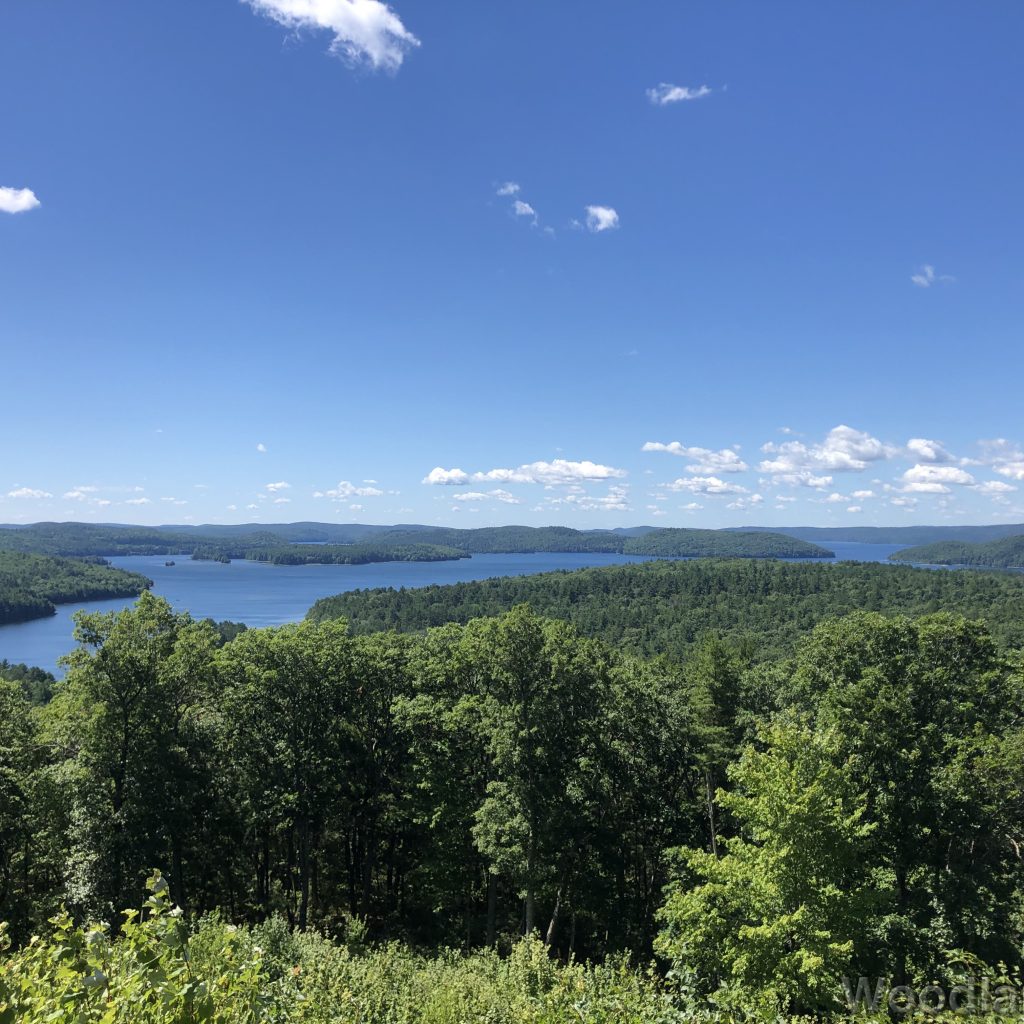 View of Quabbin Reservoir from Soapstone Hill, with blue water, vast green forest, and a sky dotted with clouds