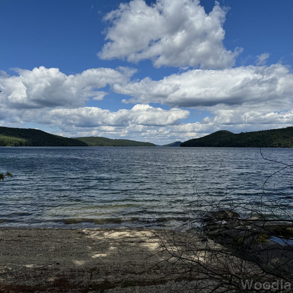 Blue water with gentle waves at Quabbin Reservoir, distant islands, and clouds casting shadows