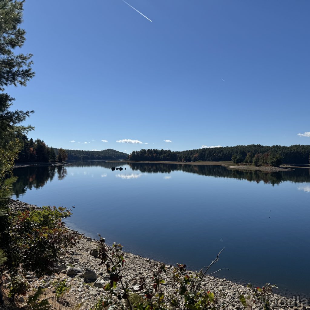 Calm blue waters of Quabbin Reservoir reflecting a few clouds in the sky