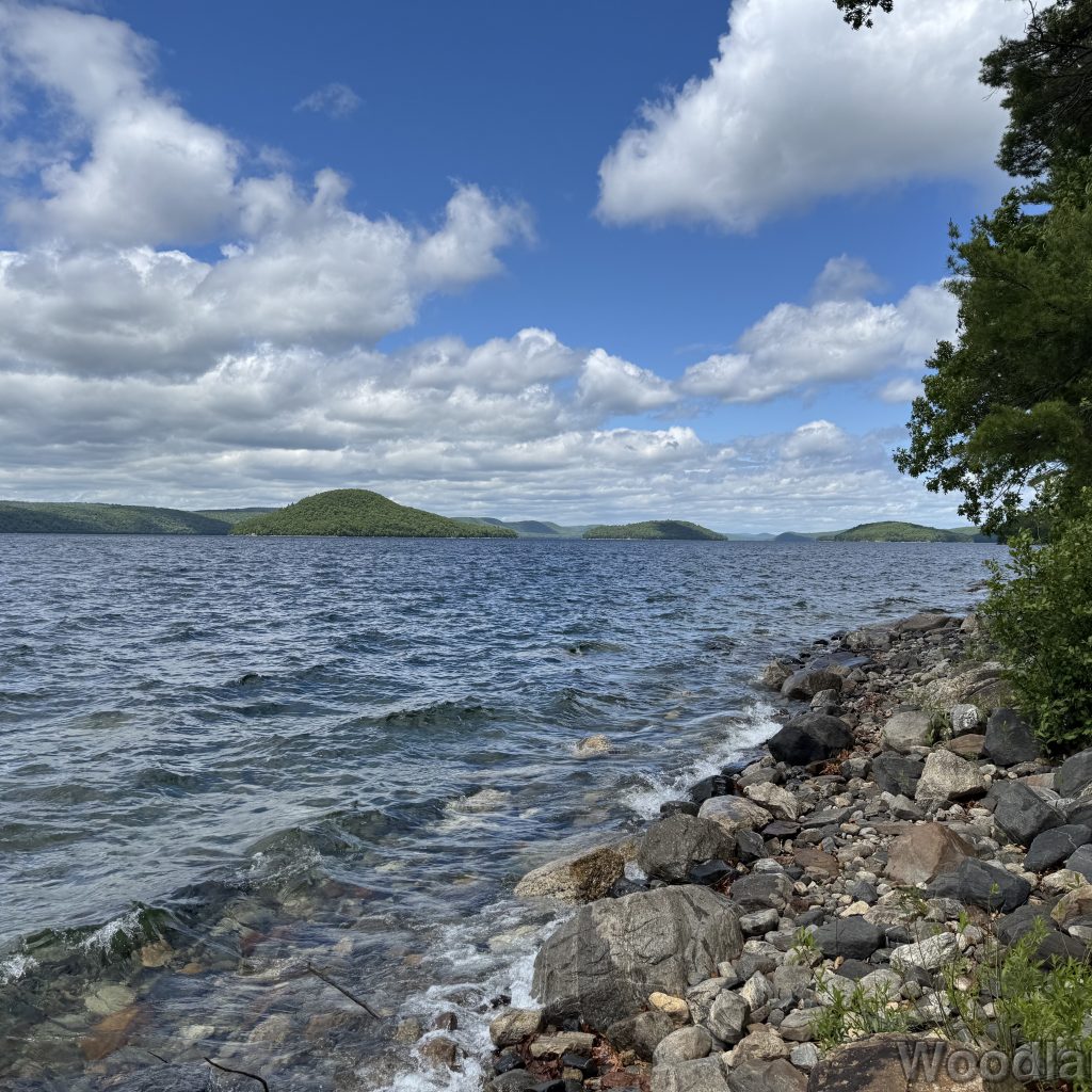 Quabbin Reservoir with choppy waves, clear water, rocky shoreline, and distant islands and hills