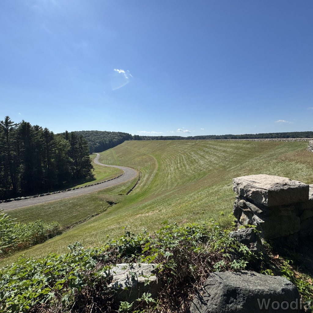 View of Windsor Dam and access road with green grass and bright blue sky