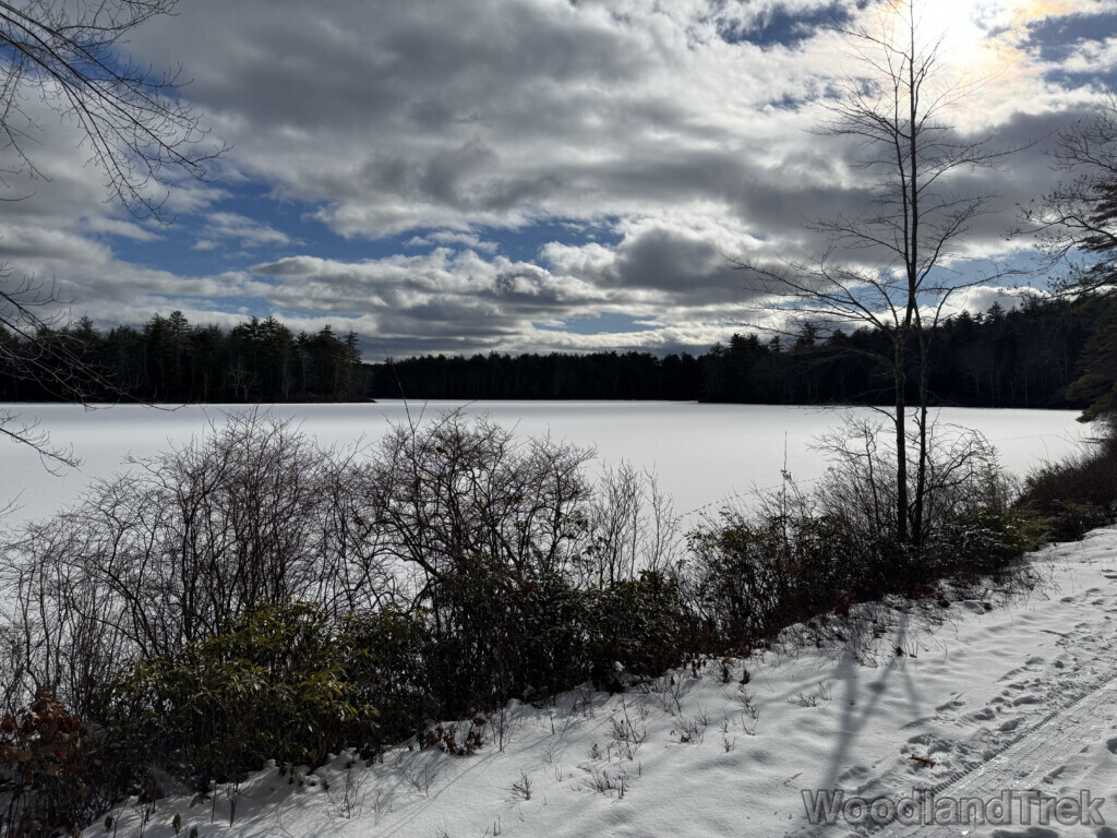 Sunlight breaking through clouds over a frozen snow-covered pond