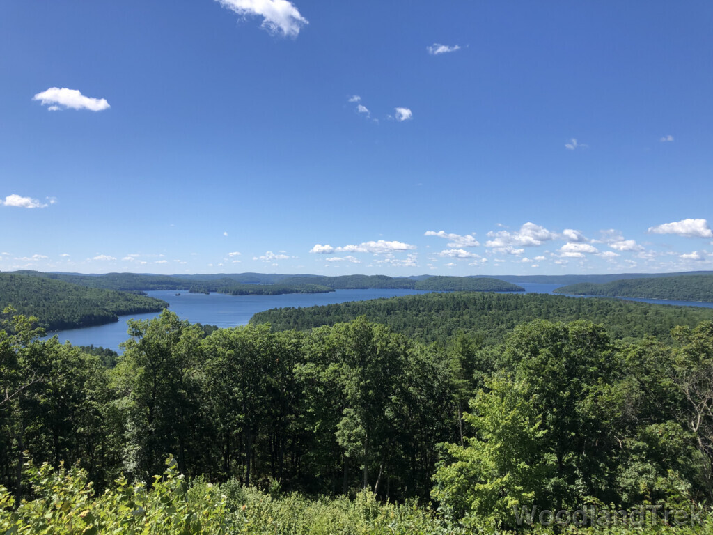 View of Quabbin Reservoir from Soapstone Hill, with blue water, vast green forest, and a sky dotted with clouds