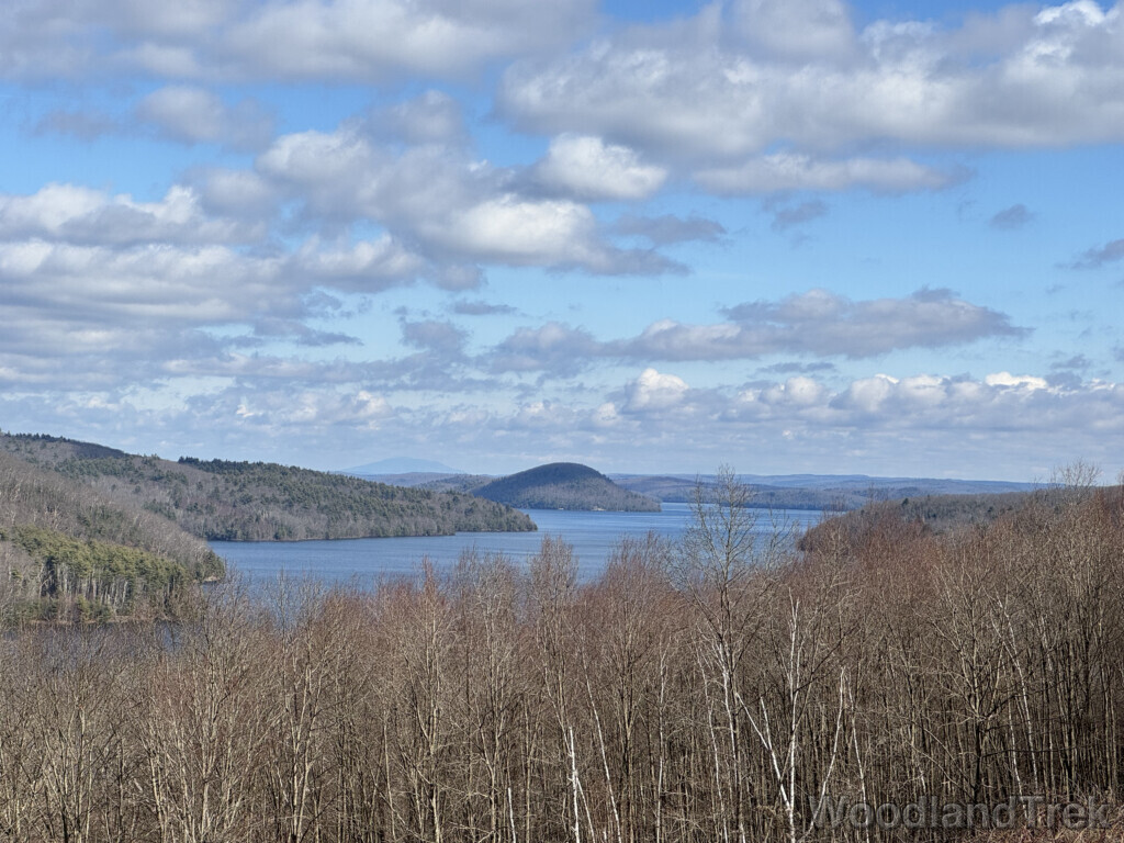 East Fork of Quabbin Reservoir viewed from Enfield Lookout, with blue water, leafless trees, and clouds casting shadows