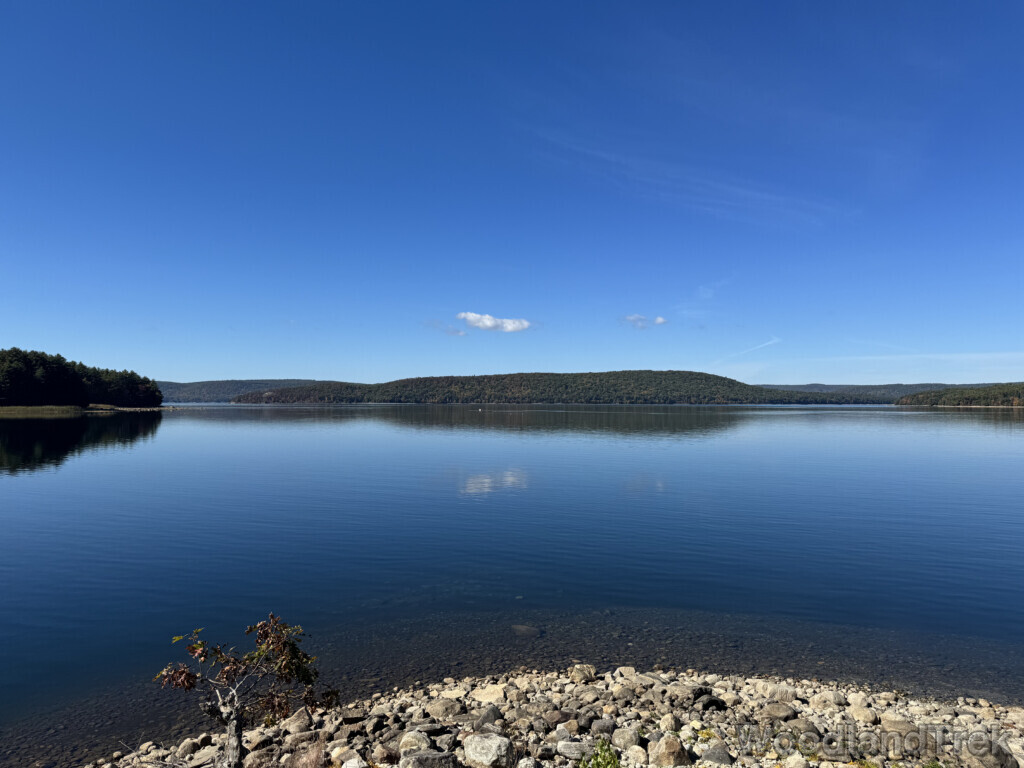 Rocky shoreline leading into clear, glassy blue waters of Quabbin Reservoir with expansive views