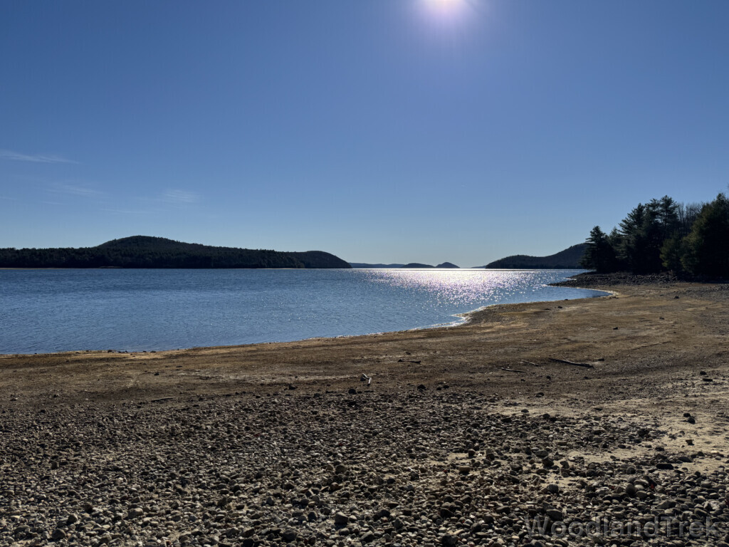 Sunlight shimmering off Quabbin Reservoir under a clear blue sky, distant terrain silhouetted