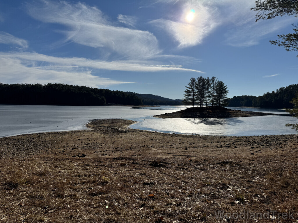 Frozen Quabbin Reservoir under wispy clouds with bright sunlight and a small pine-covered island