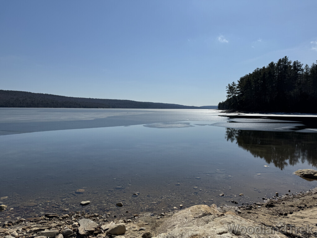 Clear calm water at Quabbin Reservoir with melting ice sheets and long distant view