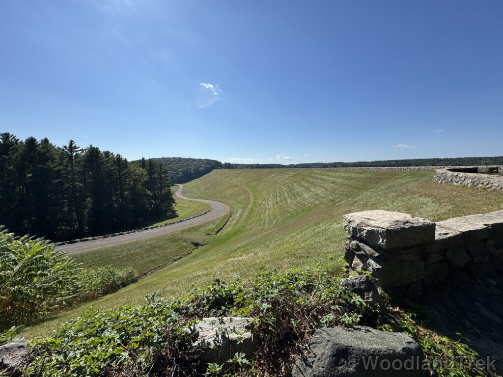 View of Windsor Dam and access road with green grass and bright blue sky