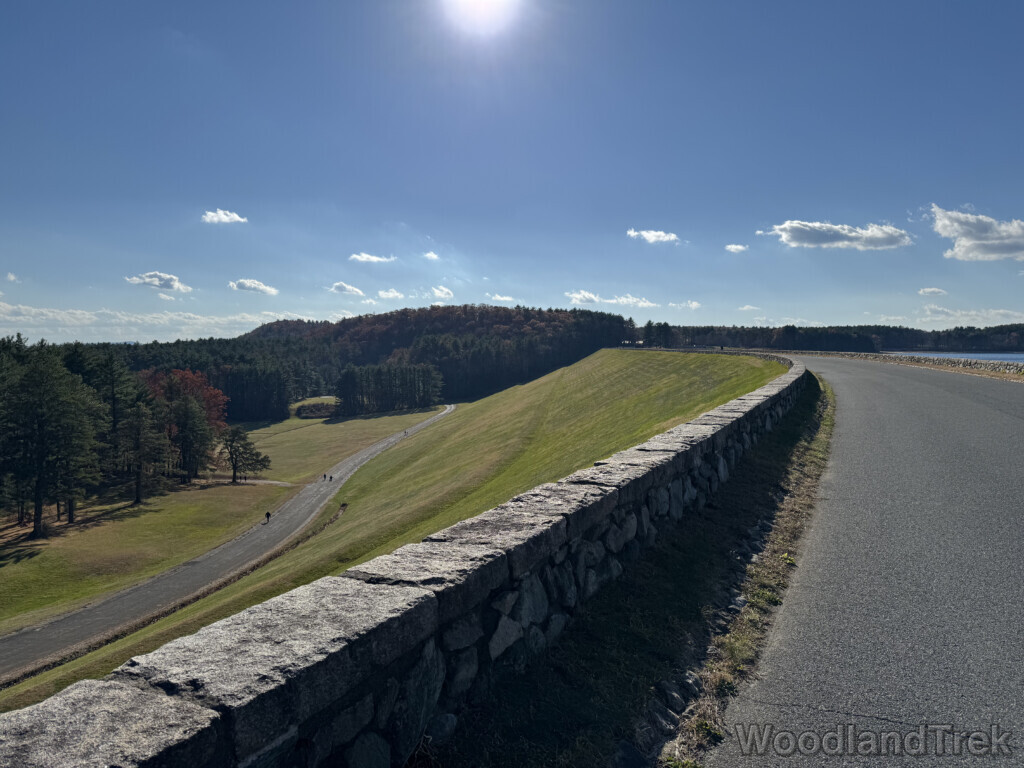 Quabbin Reservoir Windsor Dam grassy slope with access road below and forest in the distance on a bright sunny day