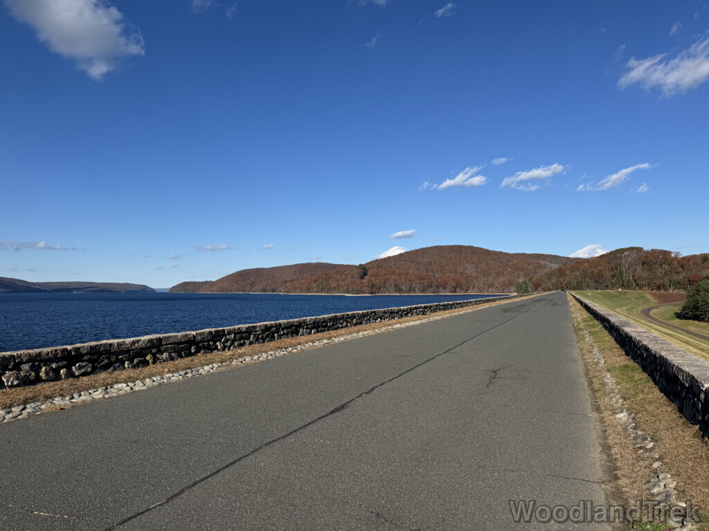Quabbin Reservoir road atop Windsor Dam facing northeast with distant hills in late November, trees mostly bare without color